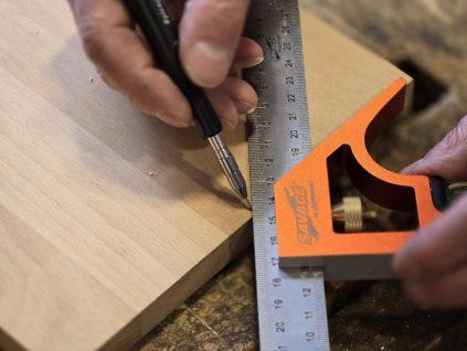 Detail orýsování dřevěné desky pomocí kombinovaného úhelníku Shinwa s posuvným nerezovým pravítkem.